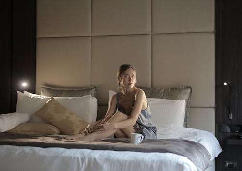 Free Woman in Blue Sleepwear Sitting on Bed Stock Photo