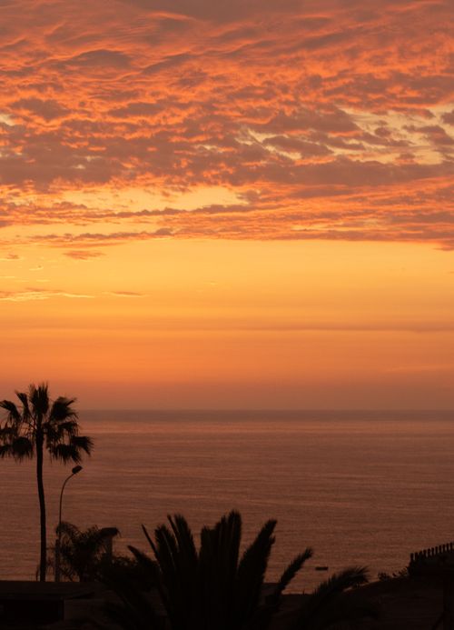 Free Capture of a breathtaking orange sunset over the Pacific Ocean in Lima, Peru. Ideal for travel inspiration. Stock Photo