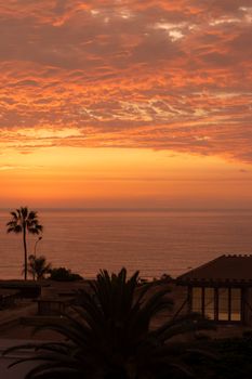Beautiful sunset view over the Pacific Ocean with palm trees and vibrant sky in Lima, Peru.
