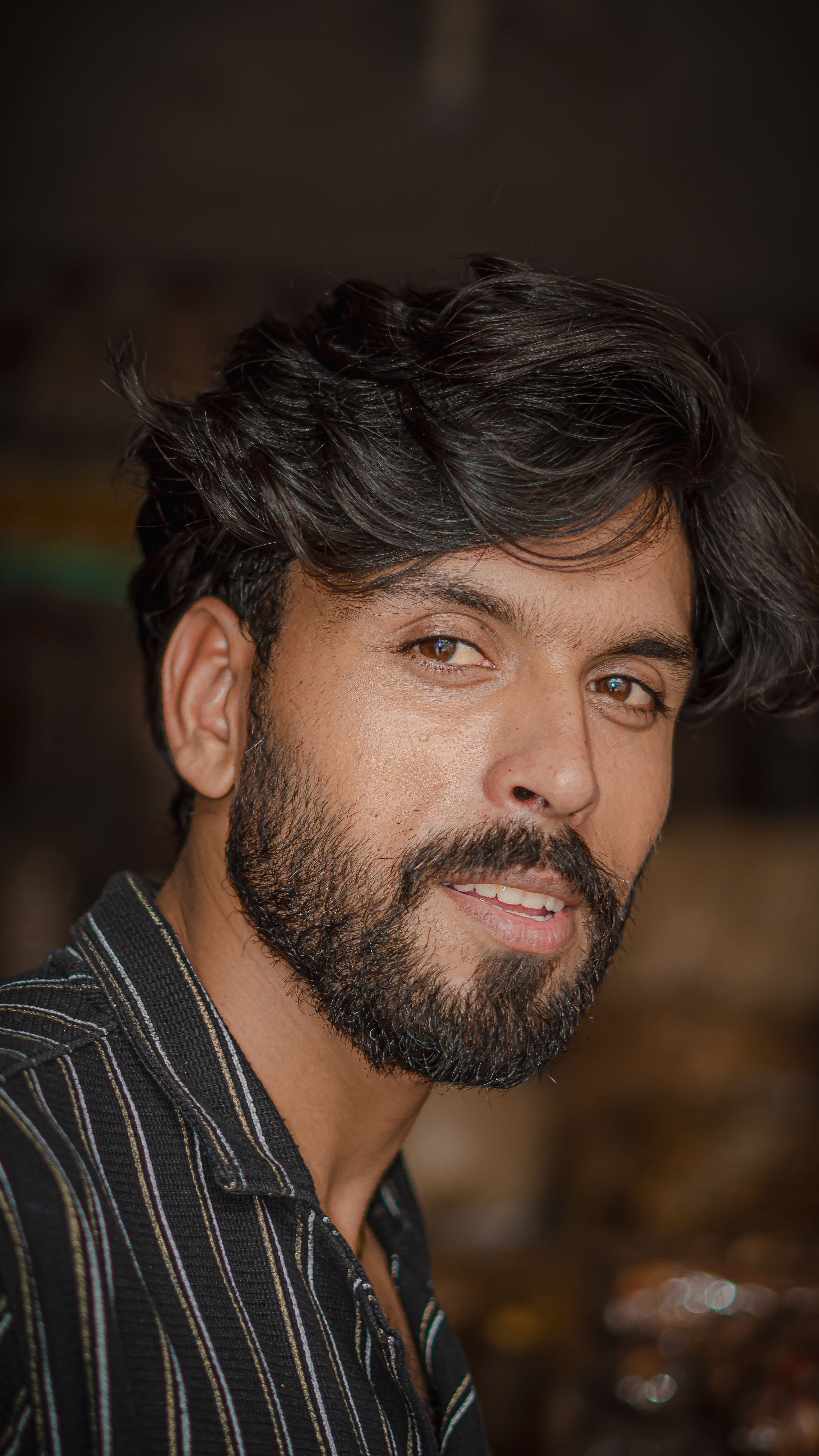 Close-up portrait of a bearded man with a relaxed expression, showcasing casual fashion.