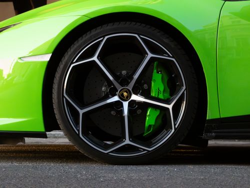 Free A vibrant close-up of a green sports car wheel with alloy rims on an urban street. Stock Photo