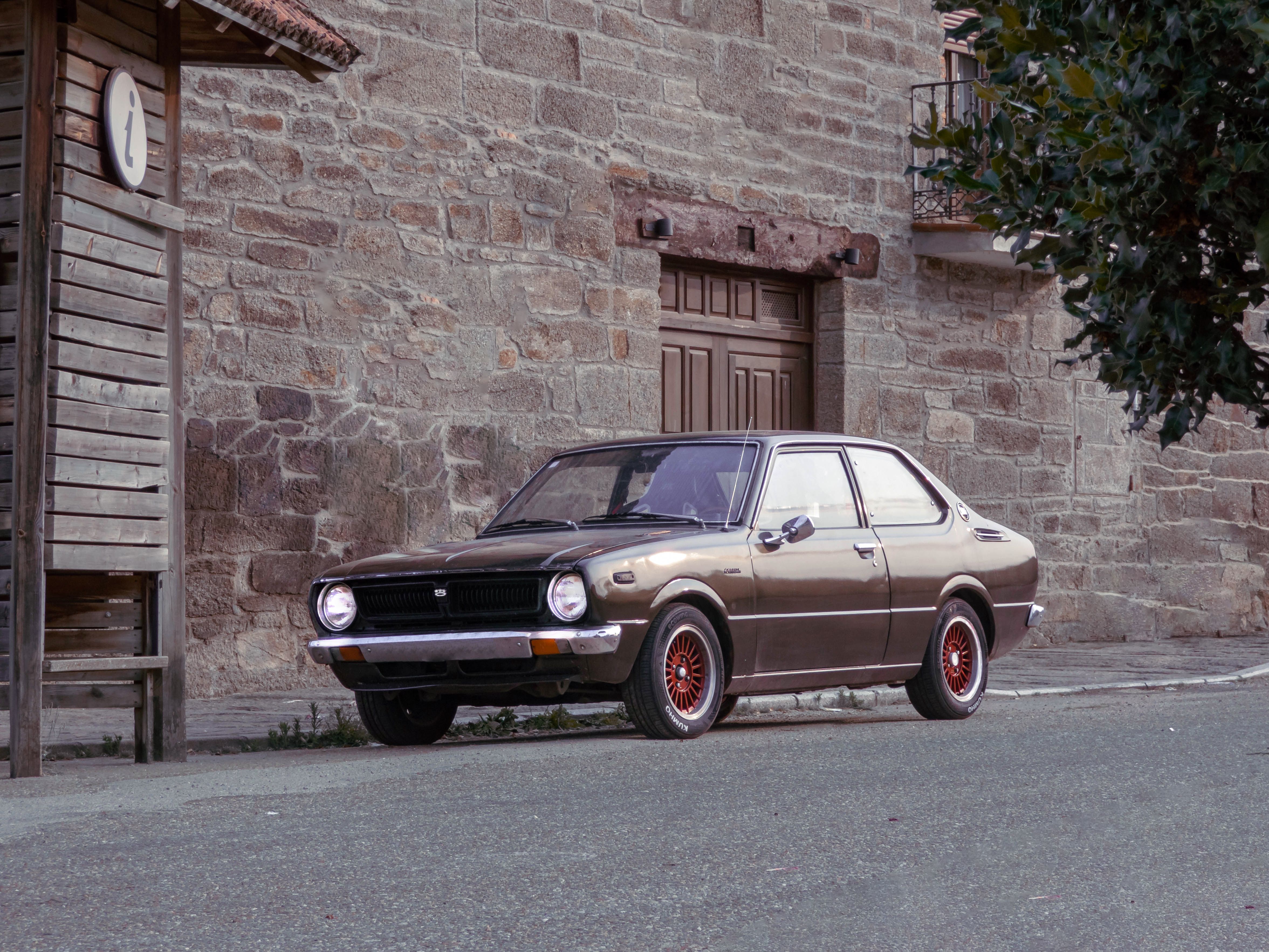Classic car parked on a historic street with rustic architecture in Villardeciervos, Spain.