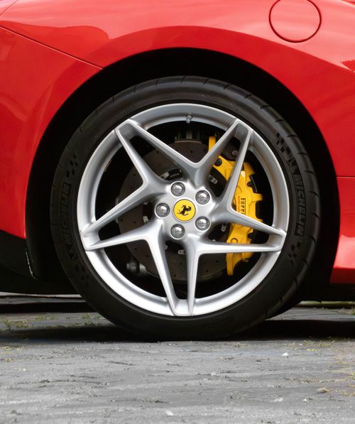 Free Detailed view of a red sports car wheel with yellow brake caliper, showcasing luxury automotive design. Stock Photo