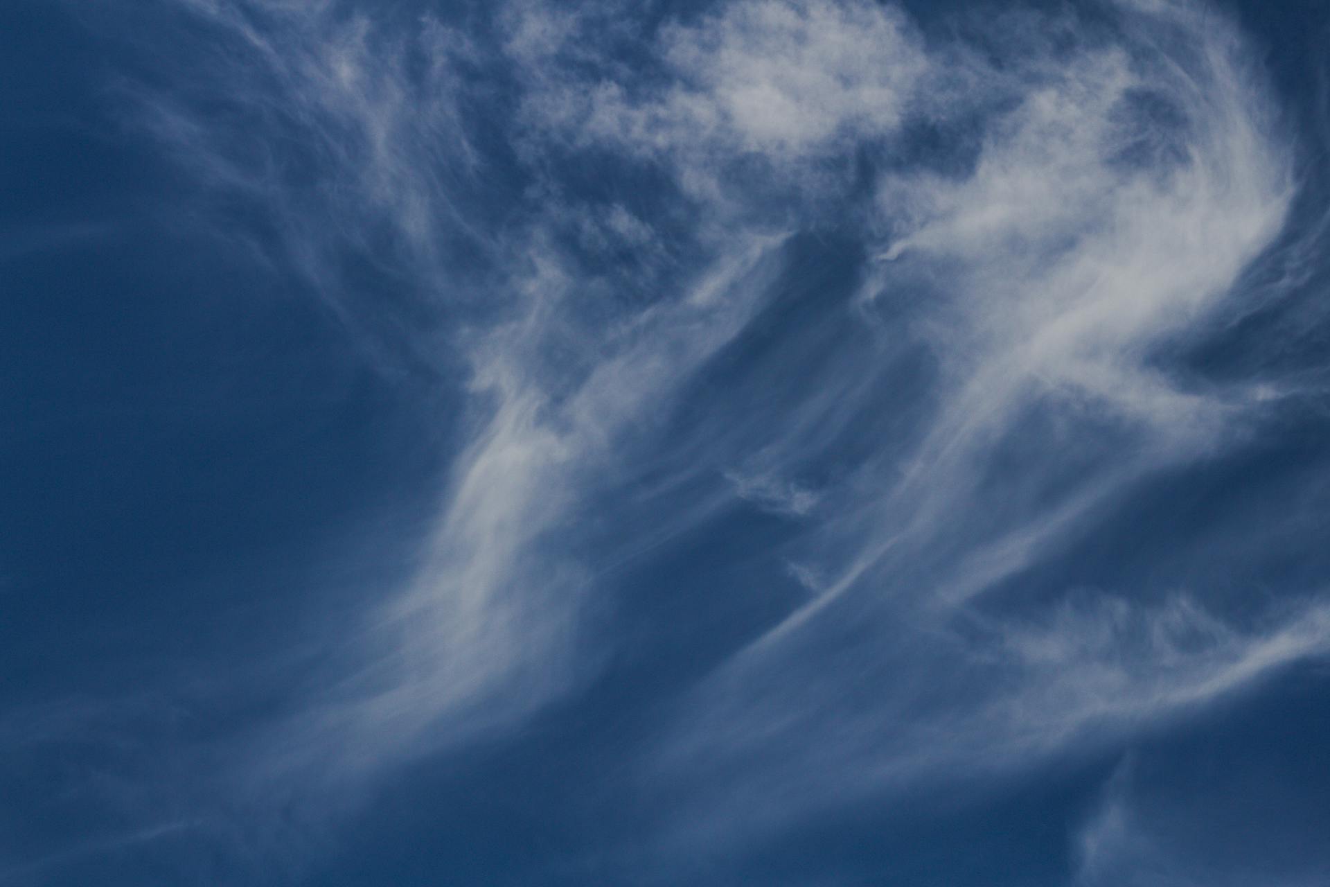 Capture of wispy cirrus clouds against a deep blue sky, symbolizing tranquil weather.