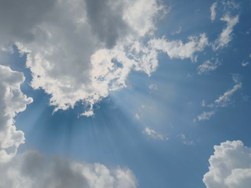 Free Dramatic sunrays pierce through scattered clouds on a clear day, creating a heavenly scene. Stock Photo