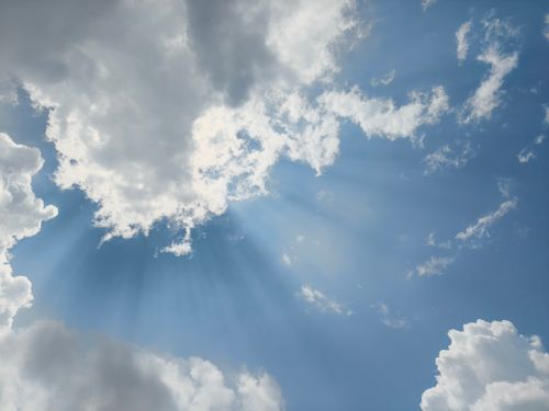 Free Vivid blue sky with sun rays streaming through fluffy white clouds in Silchar, India. Stock Photo
