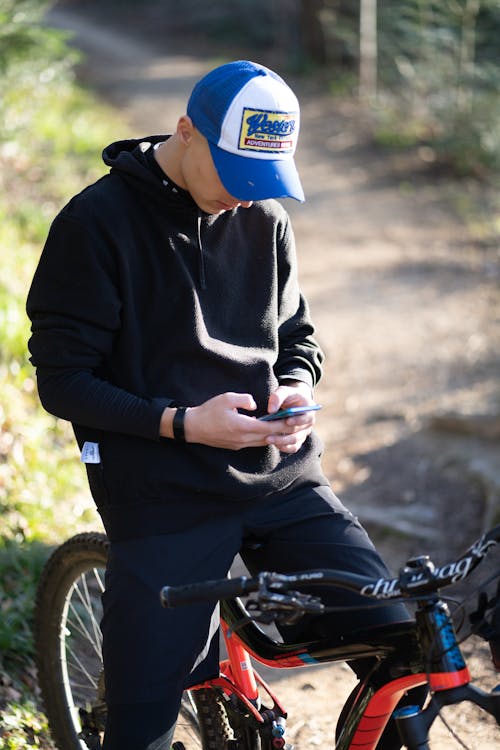 Man In Black Jacket And Blue Cap Sitting On Bicycle