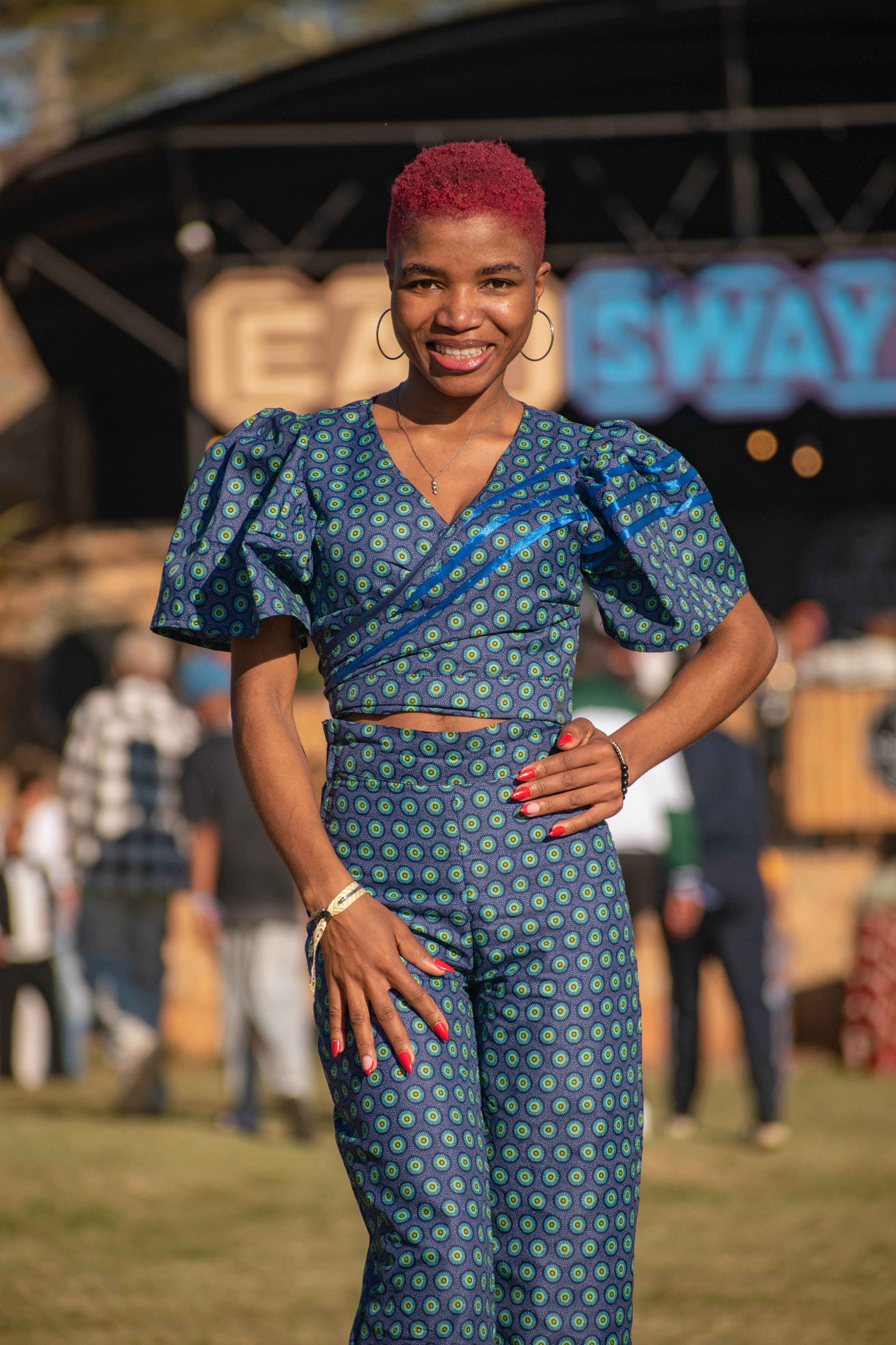 A woman in vibrant traditional clothing at an outdoor cultural gathering in Manzini, Eswatini.