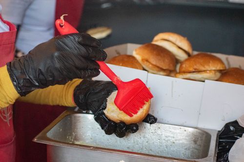 Free A street vendor uses a brush to apply sauce on sandwiches, Manzini, Eswatini. Stock Photo