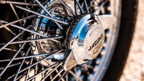 Free Detailed view of a classic Jaguar car wheel with chrome wire spokes showcasing luxury and vintage design. Stock Photo