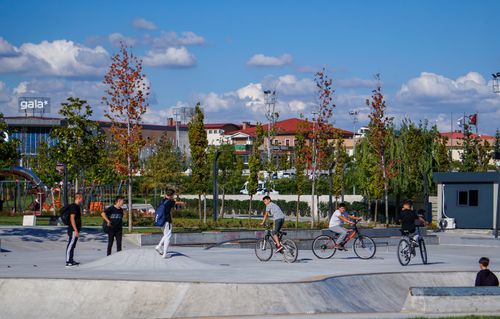 Free A lively skate park scene with teenagers on bikes and skateboards under a clear blue sky. Stock Photo