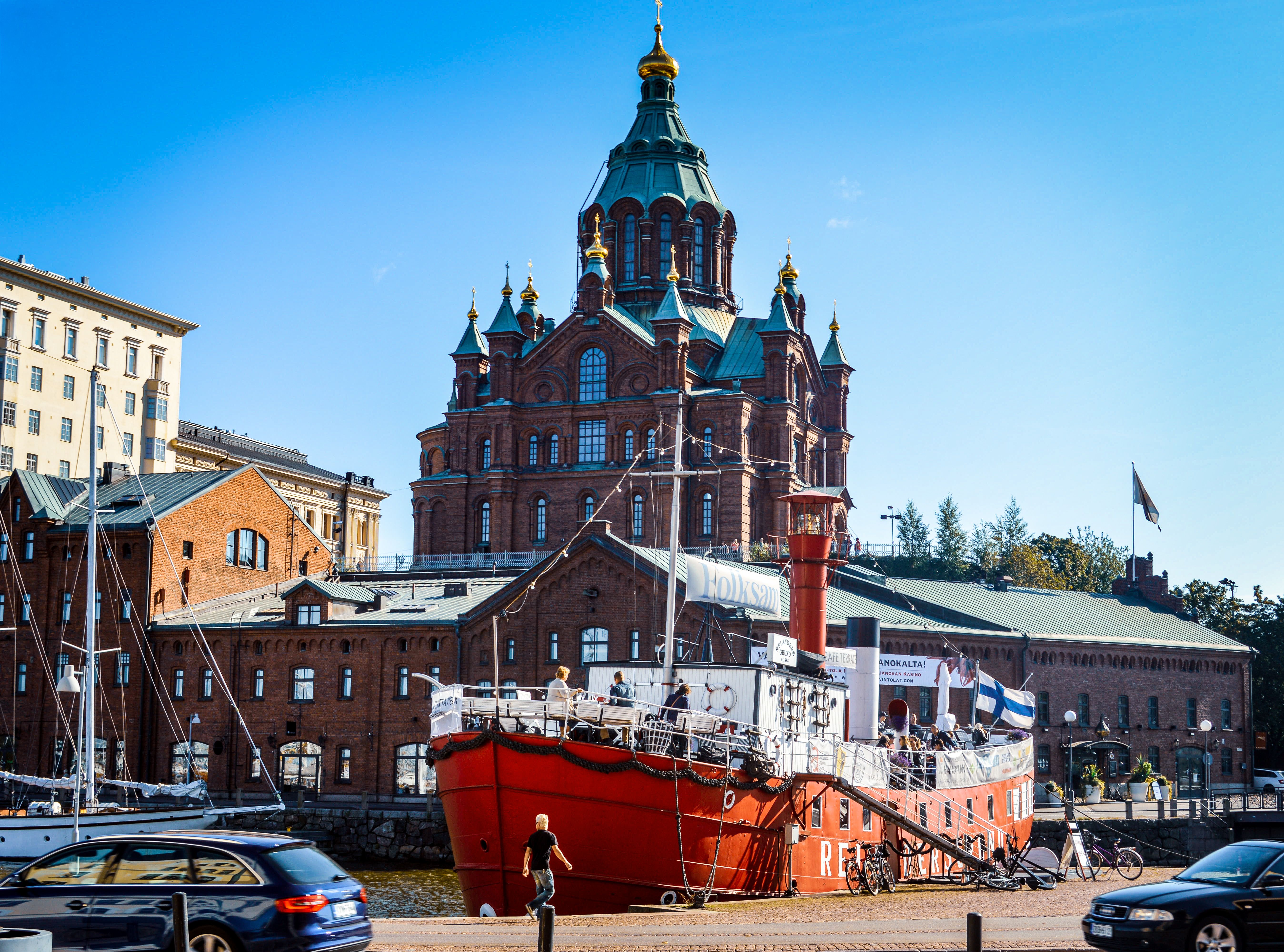 Red ship docked by Uspenski Cathedral in Helsinki, Finland on a sunny day.