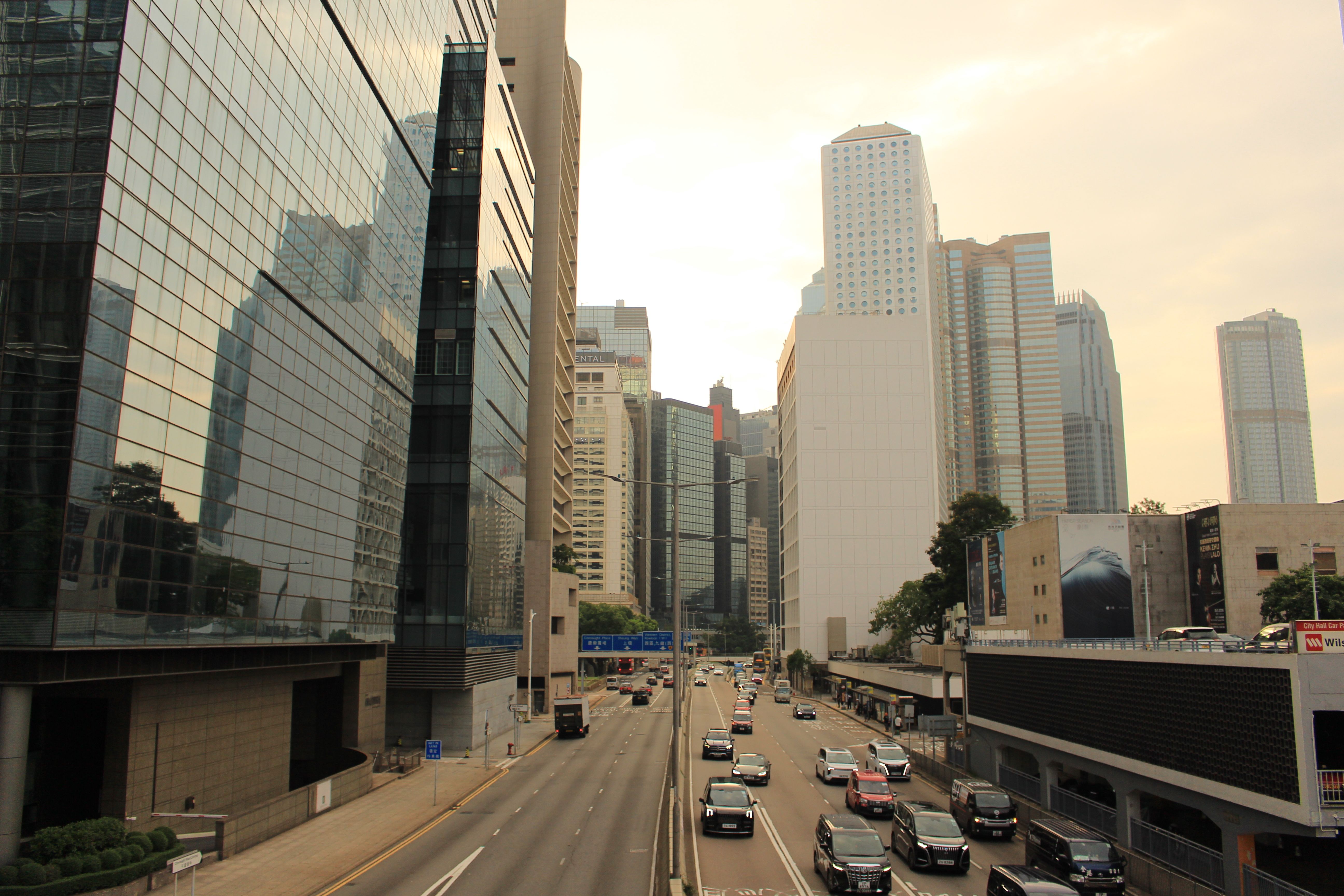 Cityscape view with skyscrapers and busy traffic on an urban street at sunset.