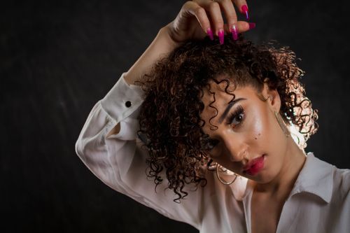 Free Portrait of a curly-haired woman exuding confidence and style, perfect for beauty and fashion themes. Stock Photo