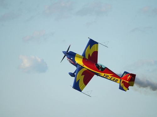 Free Colorful stunt plane executing aerobatic maneuver against a clear sky. A thrilling display of aviation skill and precision. Stock Photo