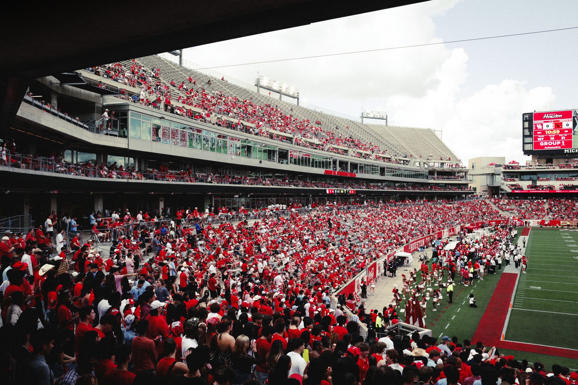 A vibrant crowd in a stadium cheering during an outdoor football game, creating an energetic atmosphere.