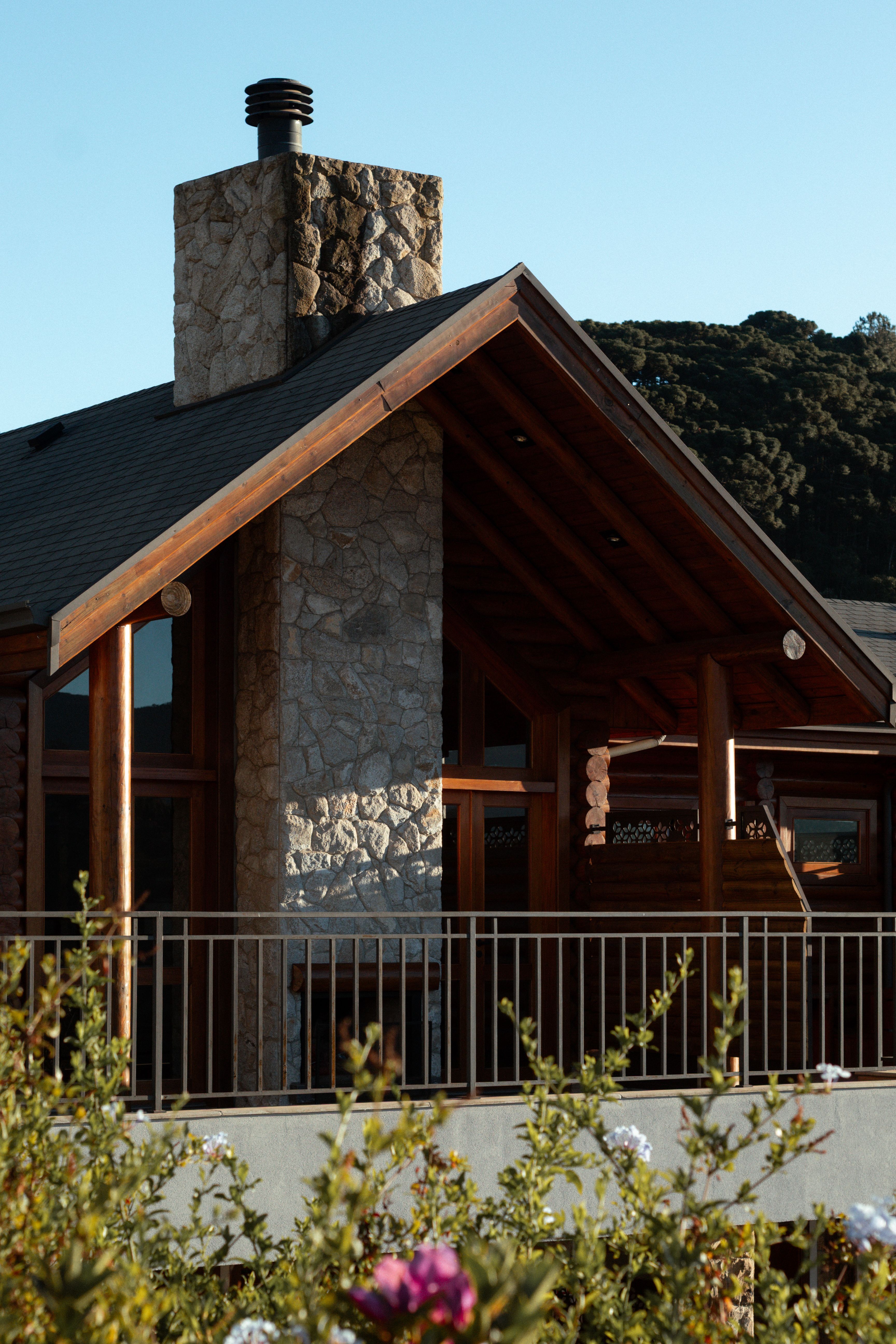 Charming log cabin with stone chimney in Monte Verde, set against lush green mountains.