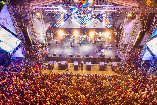 A vibrant aerial view of a concert in Banten, Indonesia, showcasing the audience and stage lighting at night.