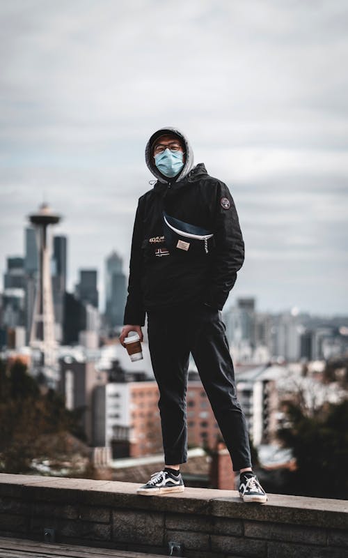 Модный этнический мужчина в маске, стоящий на крыше города
