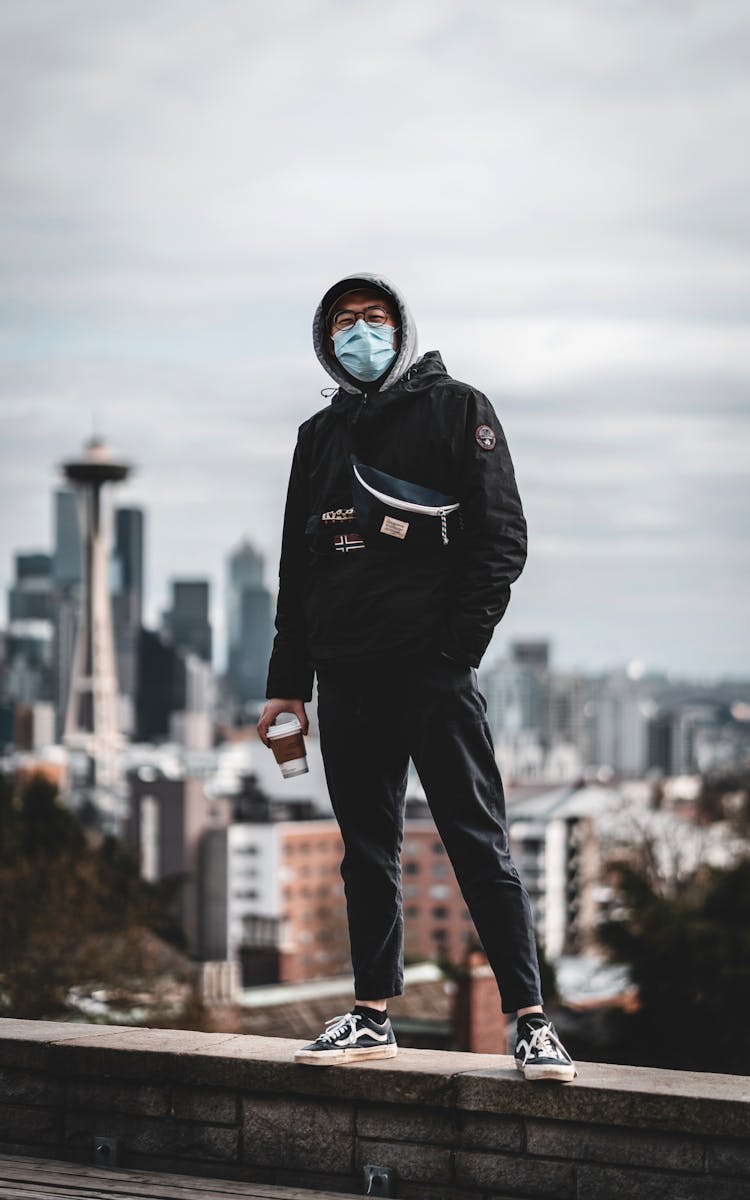 Trendy Ethnic Man In Mask Standing On Rooftop In City