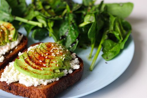 Free Delicious avocado toast with feta on wheat bread, garnished with sesame seeds and spinach salad. Stock Photo