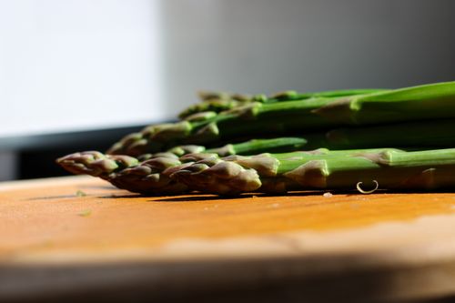 Free Close-up of fresh asparagus stalks on a wooden board in natural light. Stock Photo