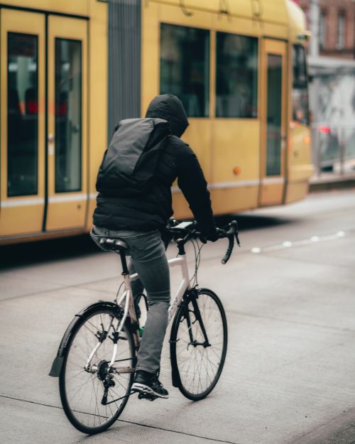 Free Cyclist on a road bike riding alongside a yellow tram on a city street. Stock Photo