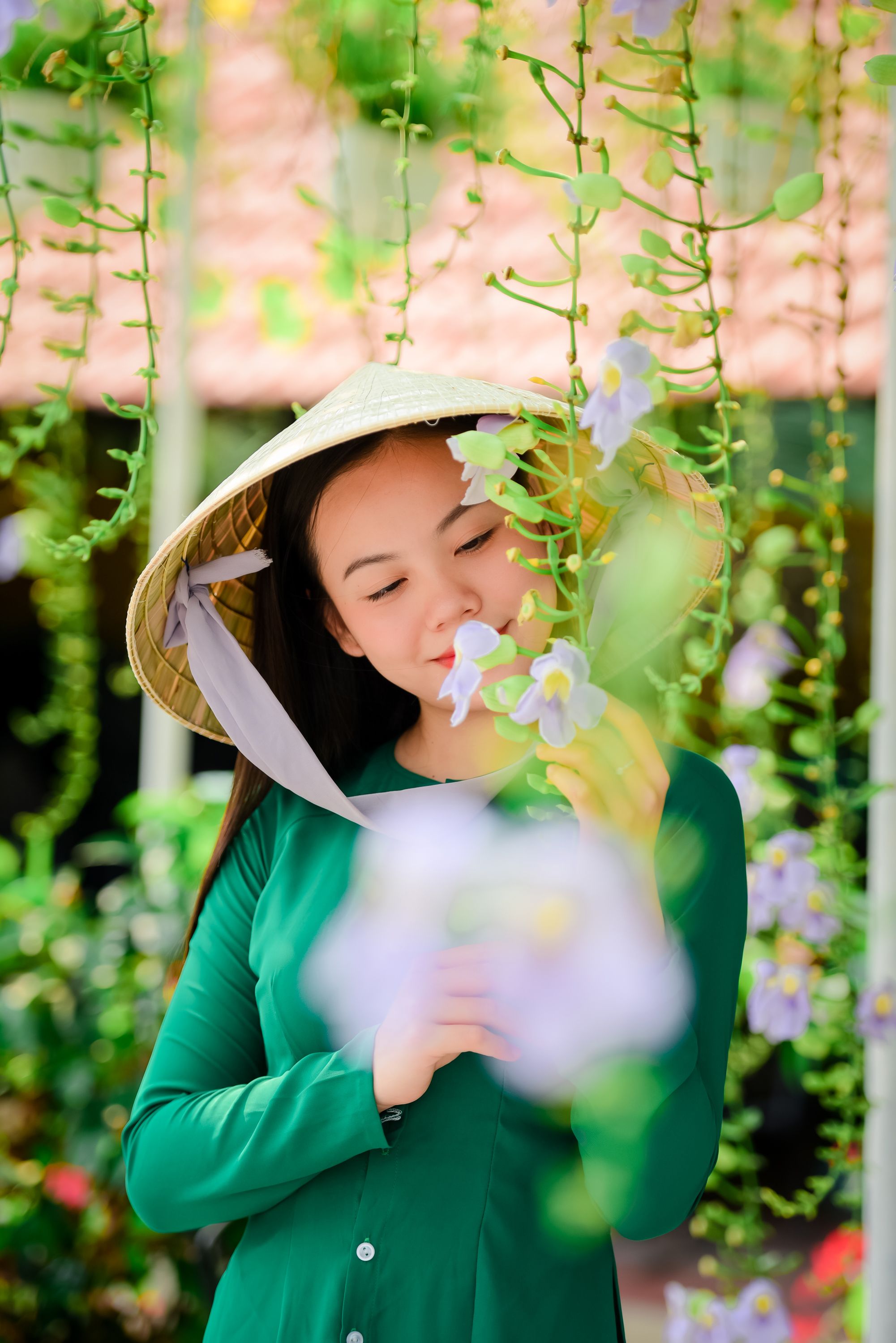 一名妇女戴着越南传统帽子，在宁静的花园里欣赏鲜花