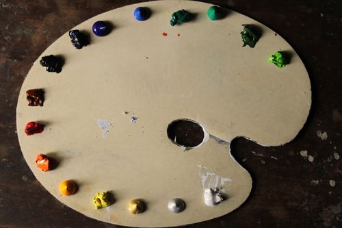Free A wooden artist palette with dabs of oil paint in various colors on a rustic background. Stock Photo