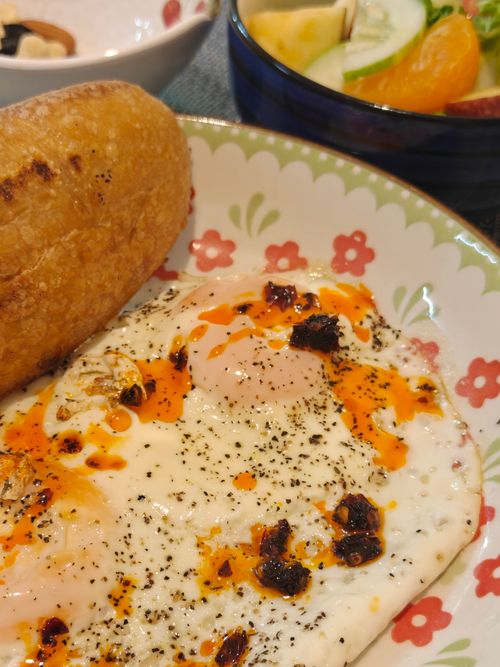 Free A close-up of a breakfast plate featuring fried eggs and bread, garnished with seasoning. Stock Photo