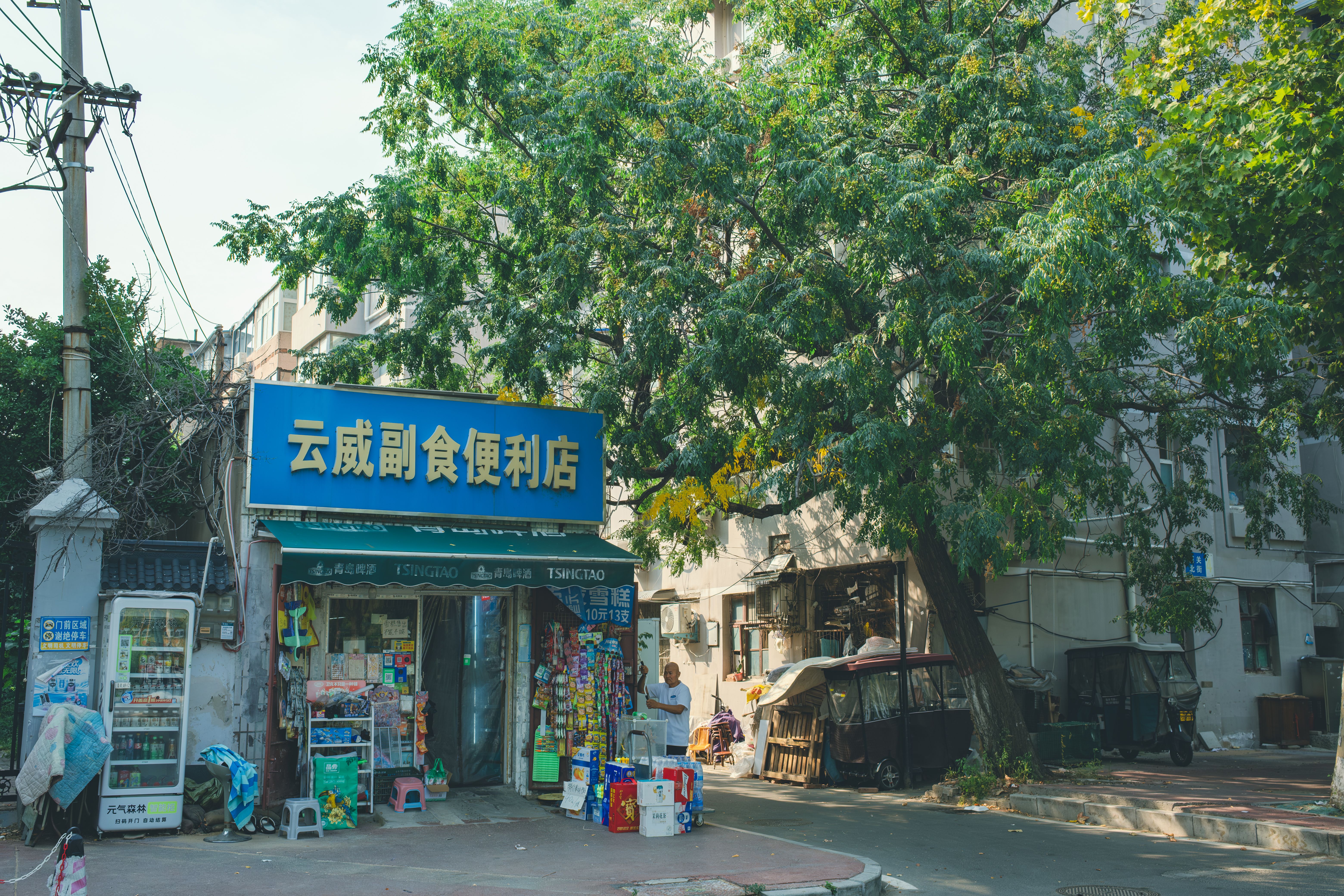 Neighborhood convenience store surrounded by trees and buildings on a sunny day.