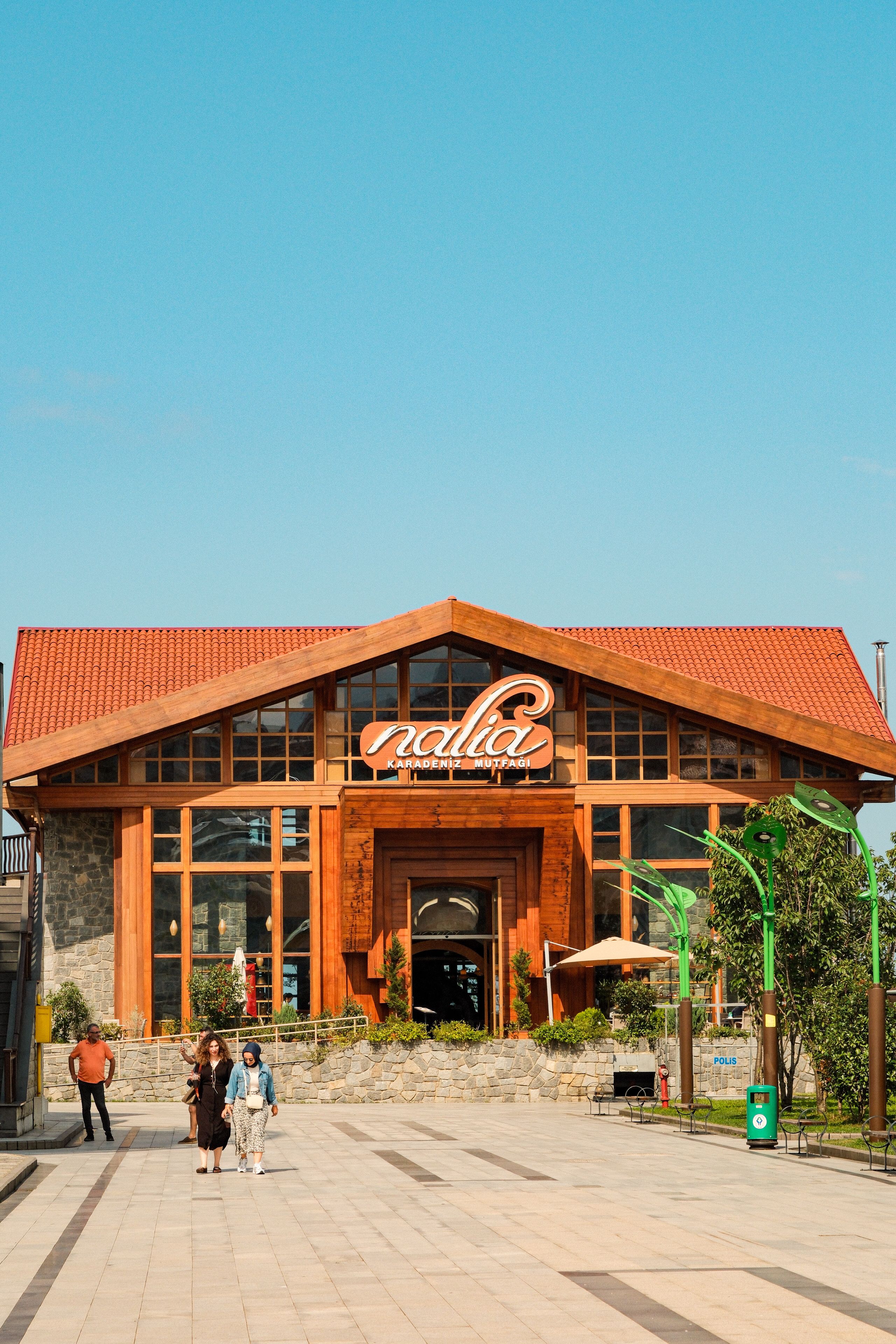 Rustic exterior of a restaurant with people in front, under a clear blue sky.