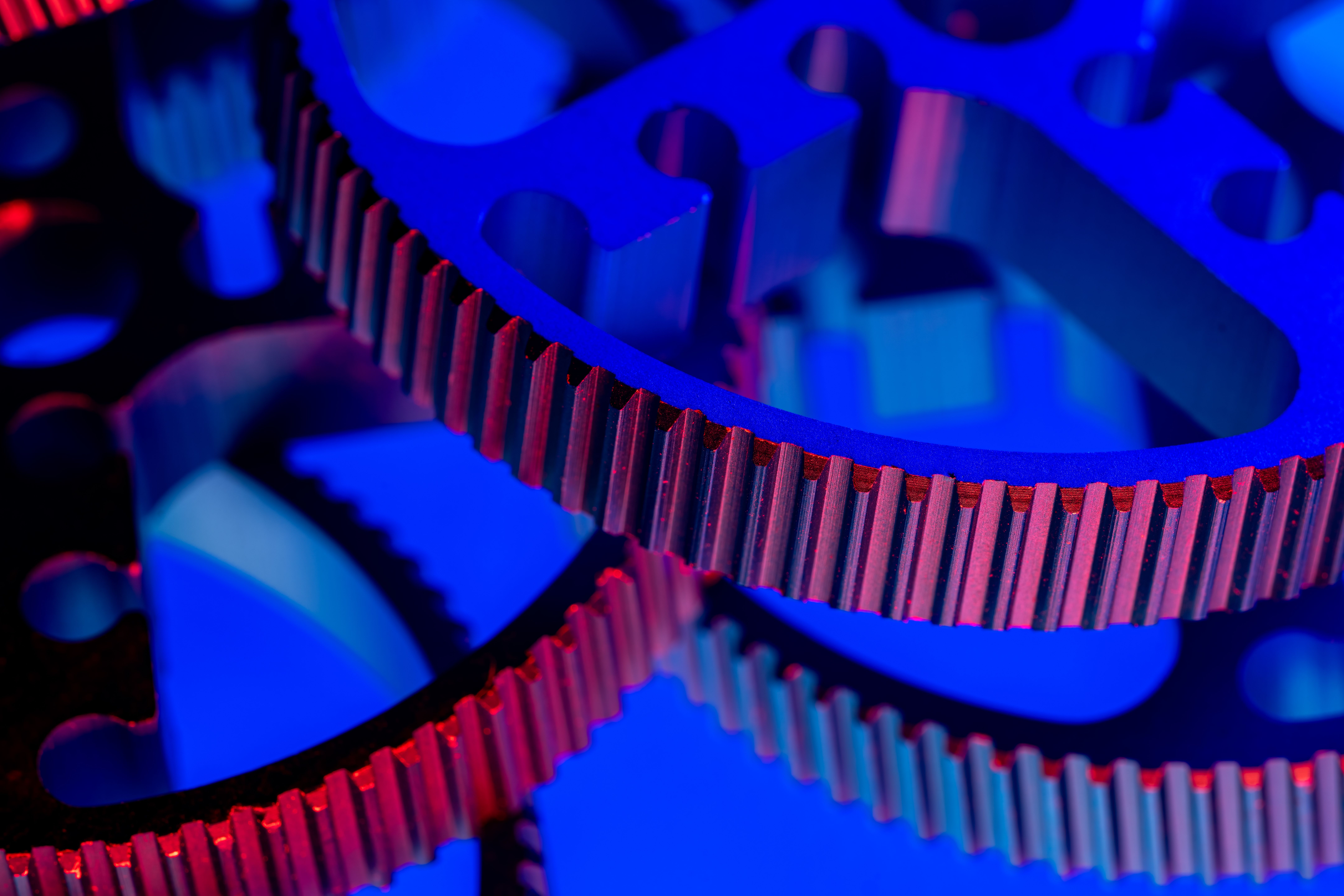 Detailed view of industrial gears highlighted with dramatic blue and red lighting.