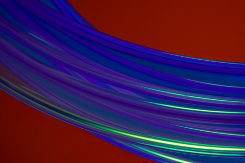 Free Colorful abstract light trails over a vibrant red background creating dynamic movement and texture. Stock Photo