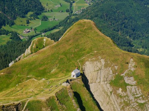 Free A stunning aerial view capturing an isolated cabin on a lush mountain in Switzerland during summer. Stock Photo