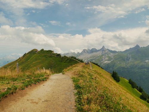 Free Discover a scenic hiking trail with stunning views of the Swiss Alps under a clear blue sky. Stock Photo