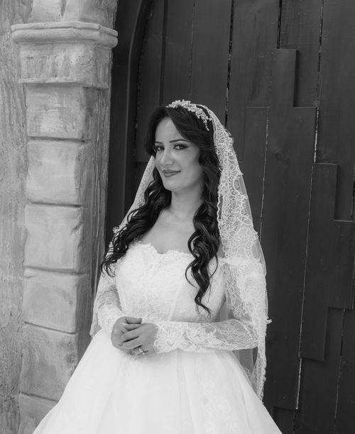 Free Beautiful black and white portrait of a bride in a lace dress standing by a rustic wooden door. Stock Photo