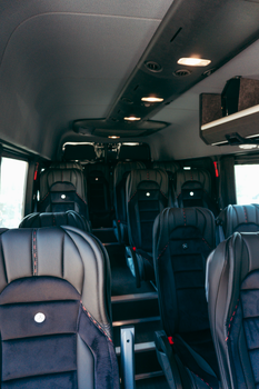 Spacious, luxurious interior of a premium passenger van with leather seats arranged in rows.
