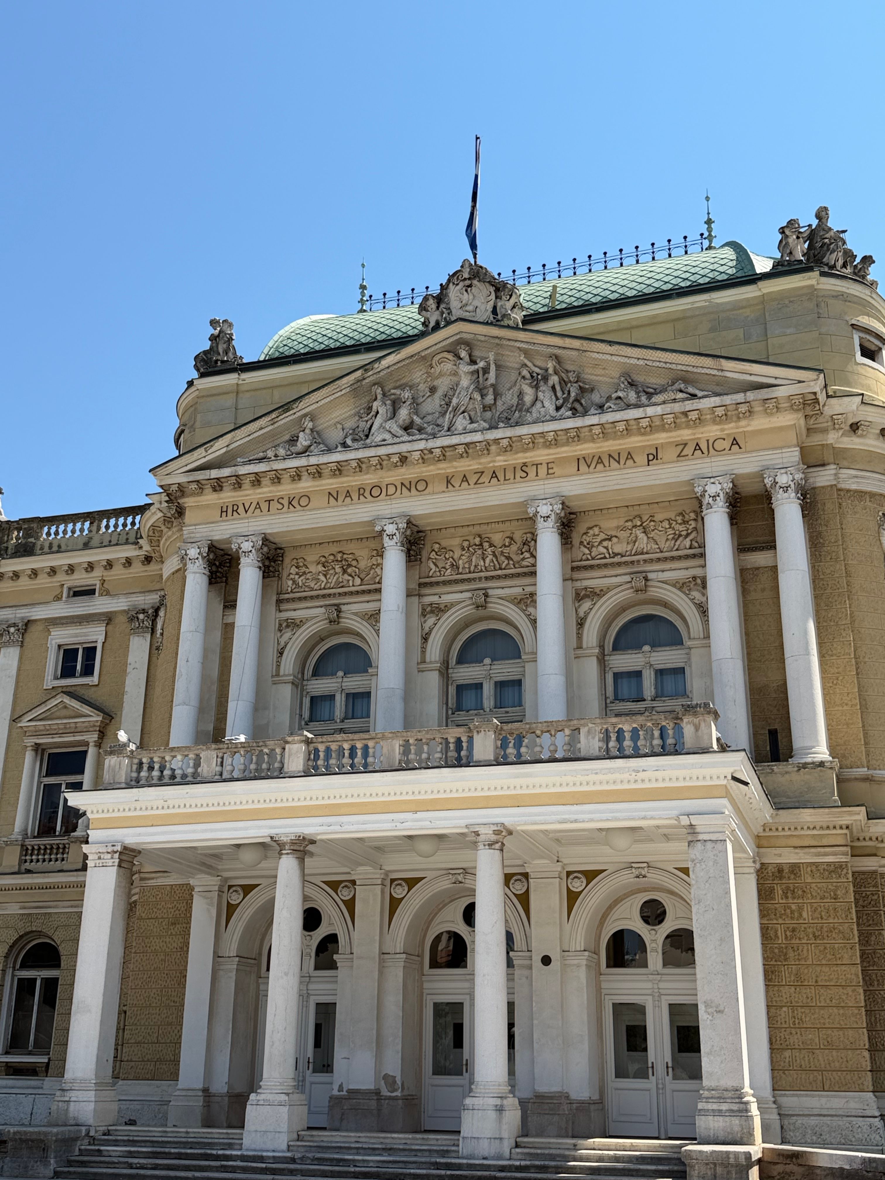 The majestic facade of Hrvatsko Narodno Kazalište in Rijeka, Croatia, under a clear sky.