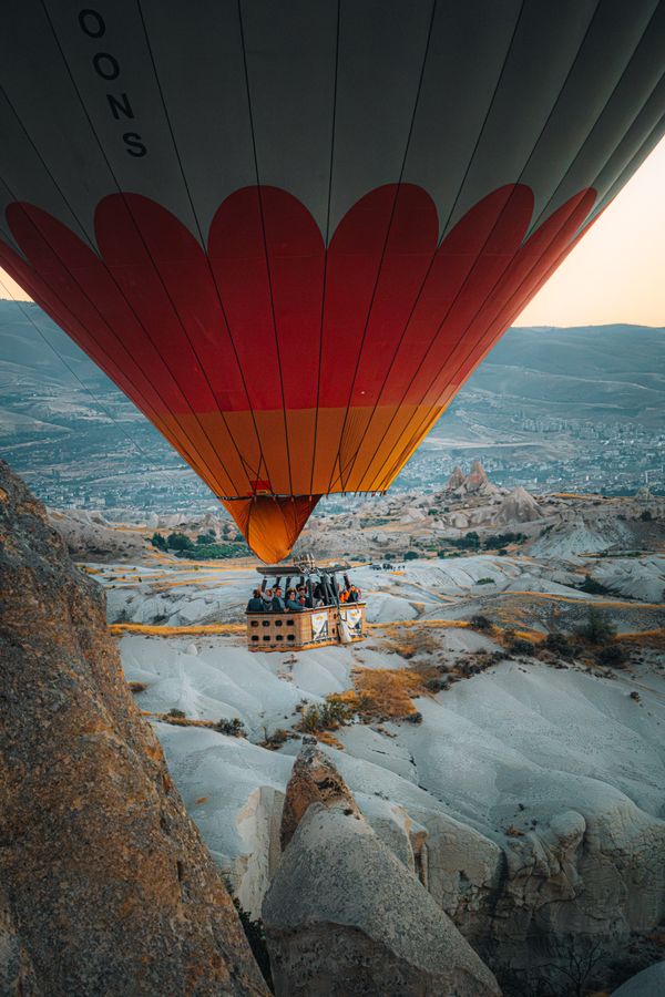Stunning view of a hot air balloon flying over Cappadocia's unique landscape at sunrise.