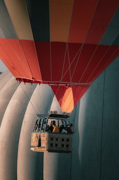 A vibrant hot air balloon with passengers soaring over the unique landscapes of Türkiye.