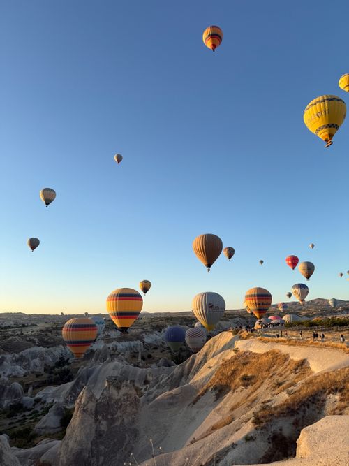 Free Captivating view of colorful hot air balloons drifting over Cappadocia's unique landscape at sunrise. Stock Photo