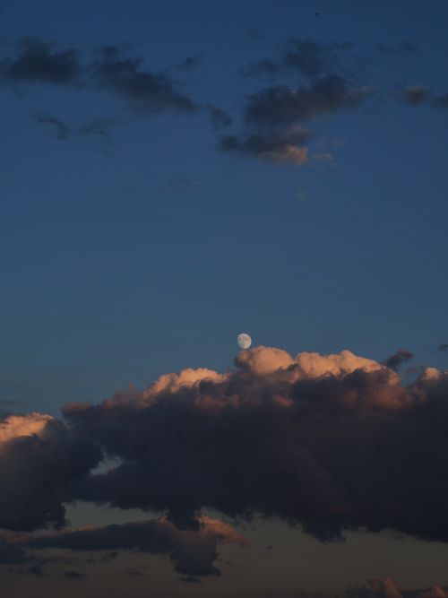 Free Capture of the moon rising above dramatic clouds during an evening sky. Stock Photo