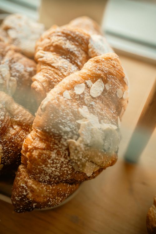 Free Close-up of almond croissants dusted with powdered sugar on a wooden surface. Stock Photo