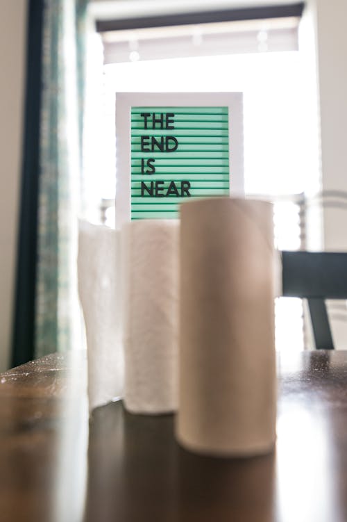 Free Rolls of paper towels on table near board with lettering Stock Photo