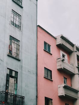Pastel-colored apartment buildings with balconies in a cityscape view.
