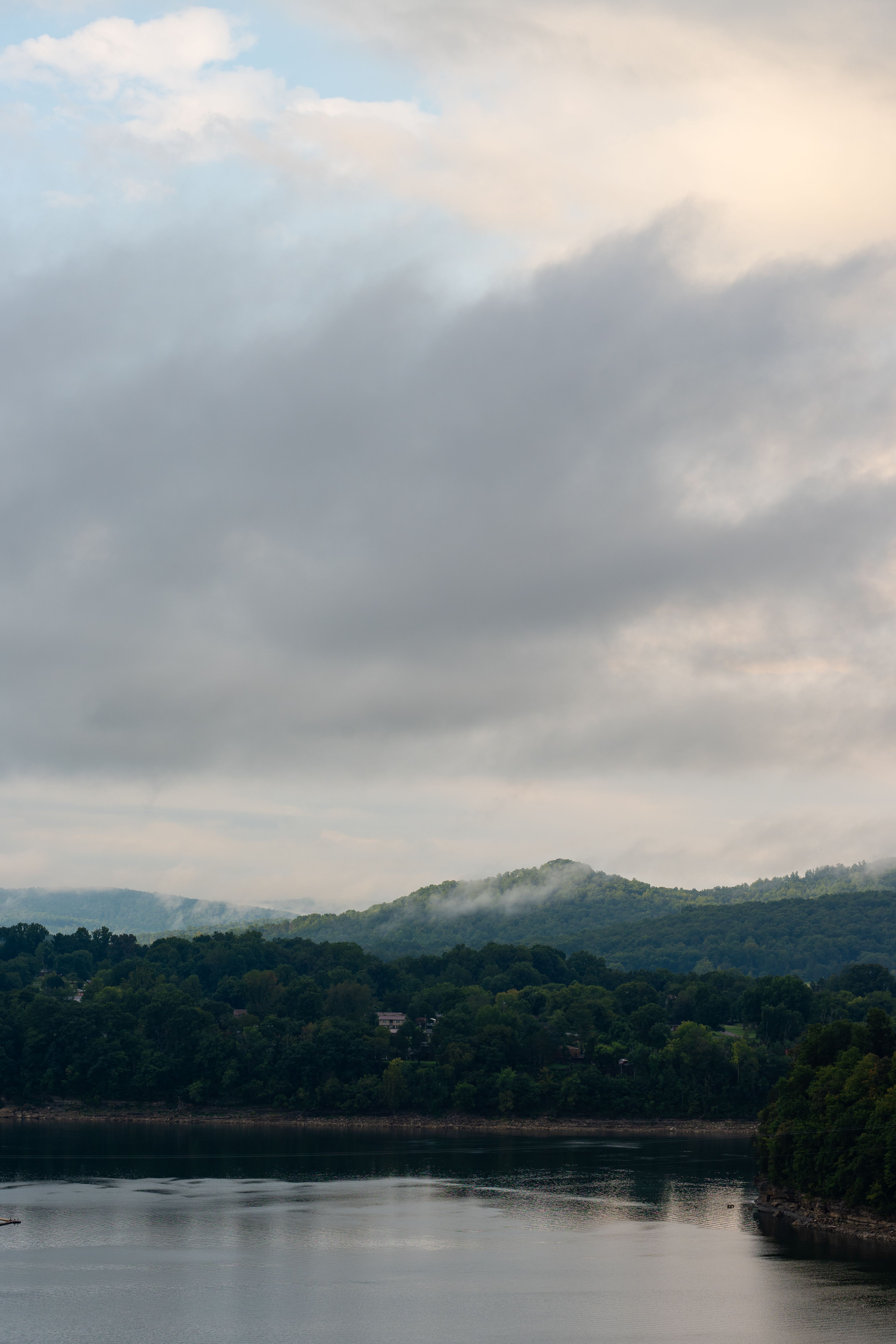 Peaceful mountain landscape with cloudy sky reflected in calm water.