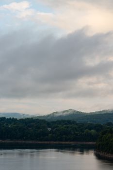 Peaceful mountain landscape with cloudy sky reflected in calm water.