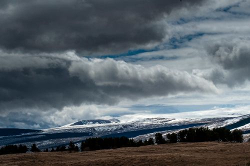 Free A breathtaking view of snowcapped mountains under dark, looming clouds, showcasing the beauty of nature. Stock Photo