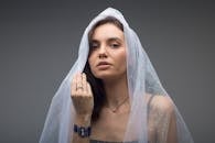 一位女士在工作室拍摄肖像，她戴着透明面纱，摆出优雅的姿势，散发着优雅与神秘的气息